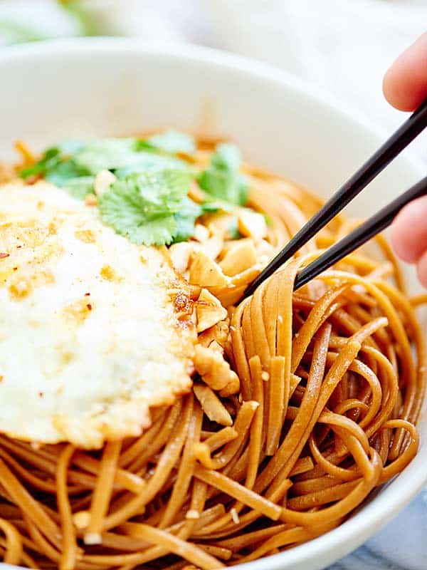 Noodles being taken out of bowl with chopsticks closeup