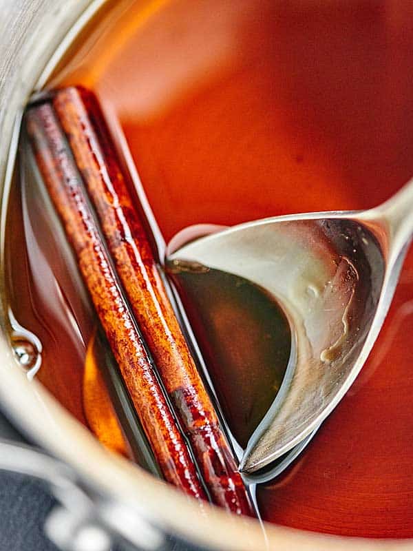 cinnamon stick being taken out of pan of sangria