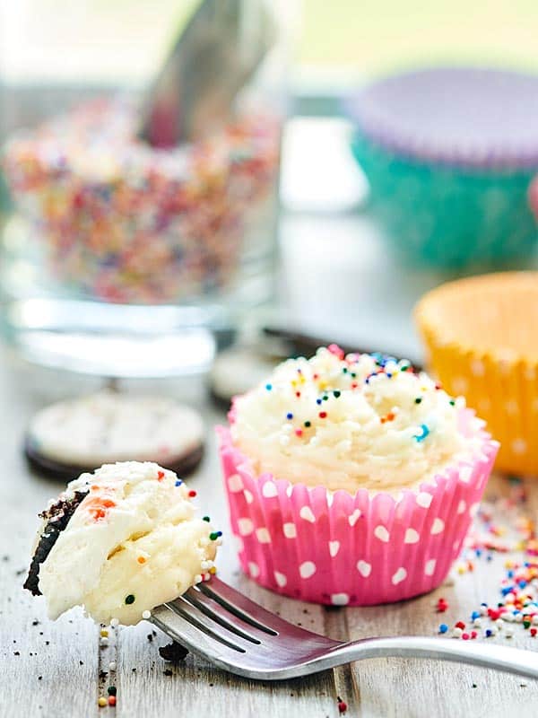 bite of cheesecake on fork next to cupcake