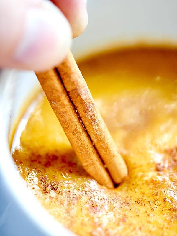 maple pumpkin spice latte being stirred with cinnamon stick