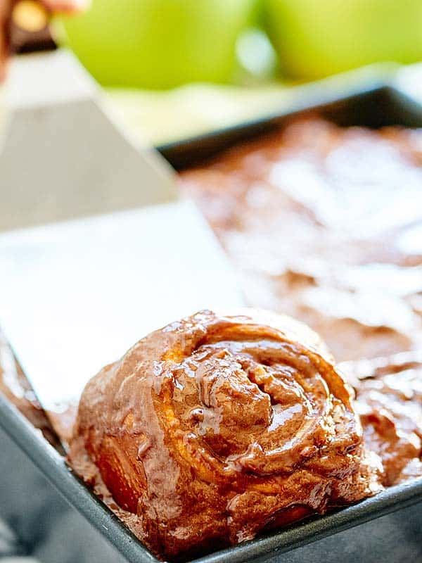 nutella cinnamon roll being lifted of baking sheet with spatula