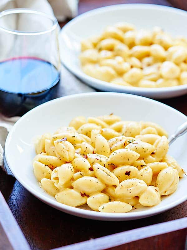 One pot mac and cheese in two bowls next to glass of red wine