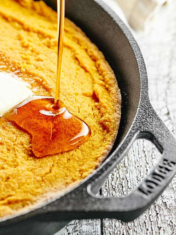 honey being drizzled on cornbread in skillet