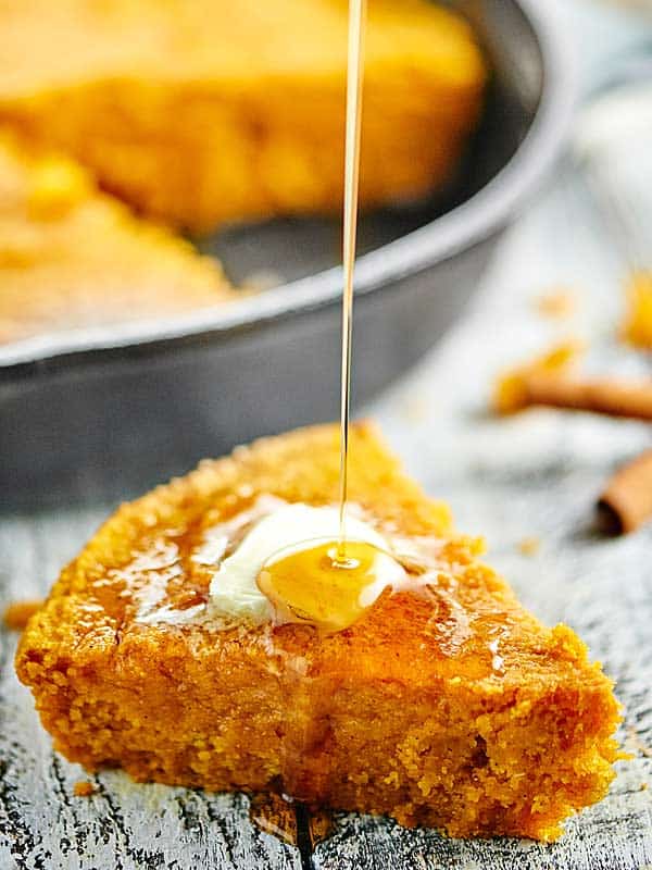 slice of pumpkin cornbread being drizzled with honey