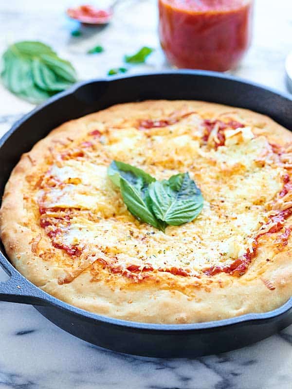 Side/above shot of pizza with basil leaves in the center