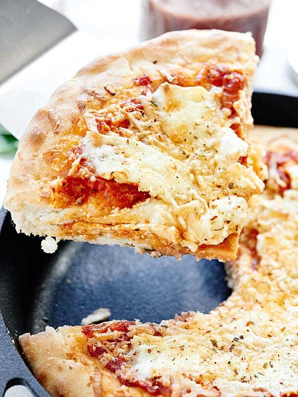 Slice of pizza being taken out of skillet