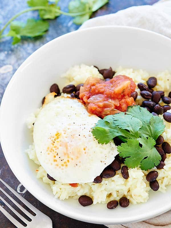 rice and beans with egg, cilantro, and salsa above