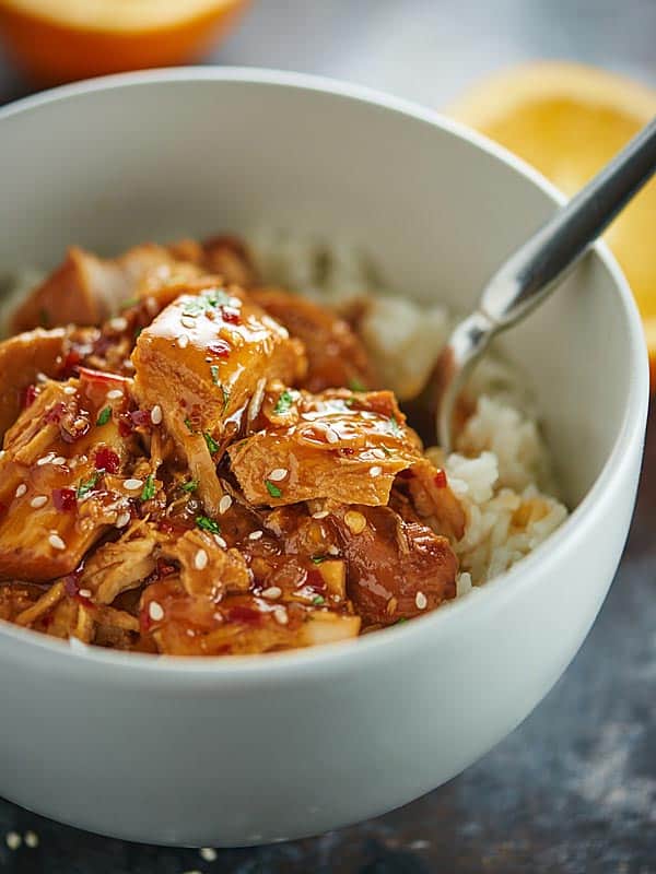 Bowl of rice and orange chicken with a fork