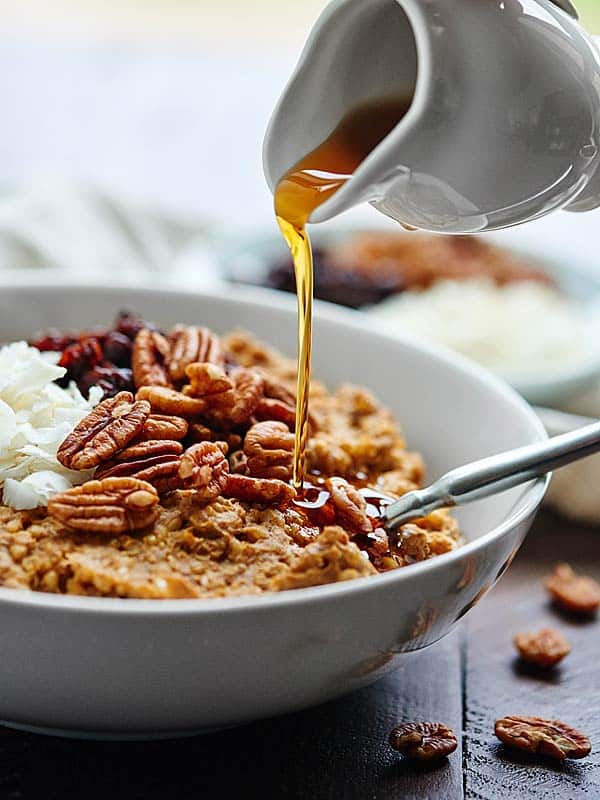 crockpot pumpkin oatmeal in bowl being drizzled with maple syrup