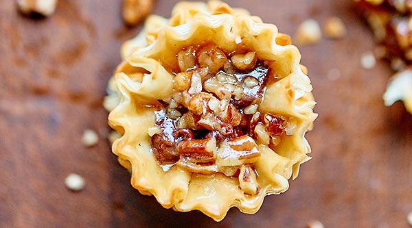 These pecan pie bites are cute, bite sized, quick & easy to make, & filled w/ a maple bourbon caramel. Chocolate chips are optional, but highly recommended! showmetheyummy.com #thanksgiving #pecanpie