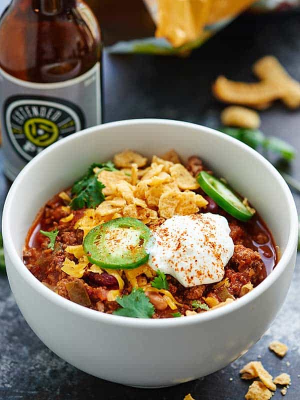 bowl of slow cooker beef chili next to beer bottle