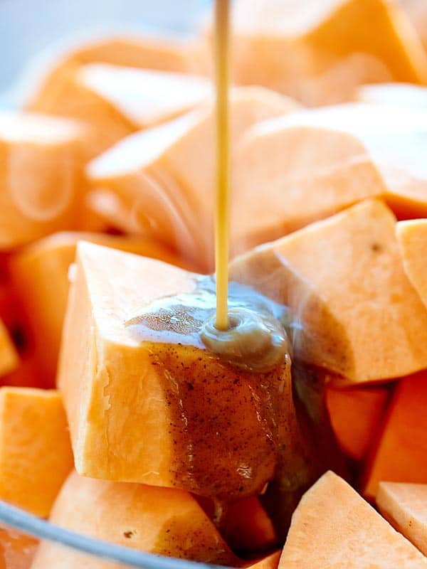 glaze being drizzled over cubed sweet potato