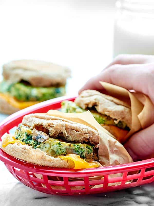 Breakfast sandwiches in basket, one being picked up