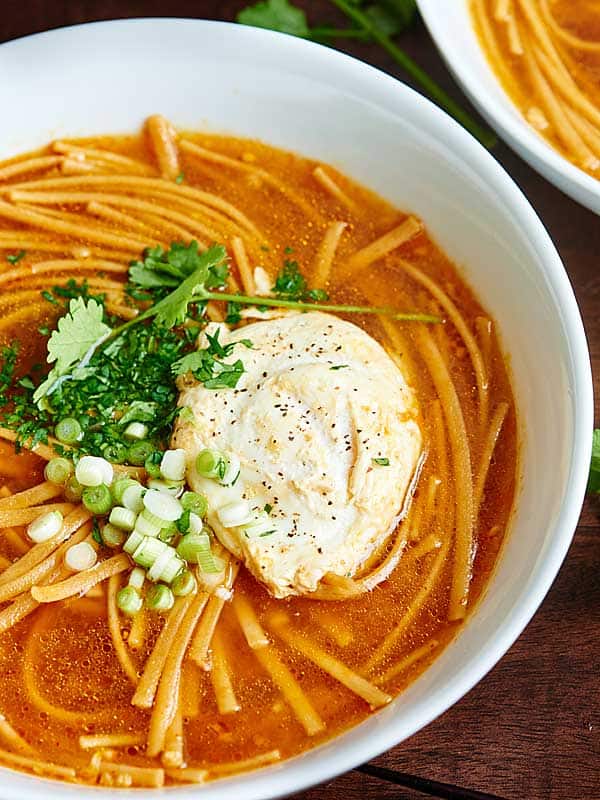 bowl of soup with garnishes and egg above