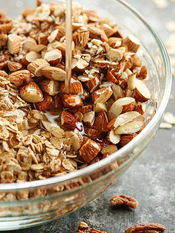 Honey being drizzled into bowl of granola ingredients