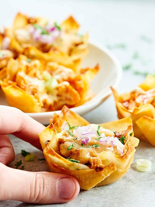 chicken wonton cups on plate, one being picked up off counter in front