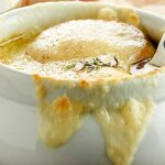 This French Onion Soup Recipe is the perfect appetizer for two! A flavorful beef and onion broth is topped with baguette, parmesan, and gooey swiss cheese! showmetheyummy.com #frenchonionsoup #appetizer