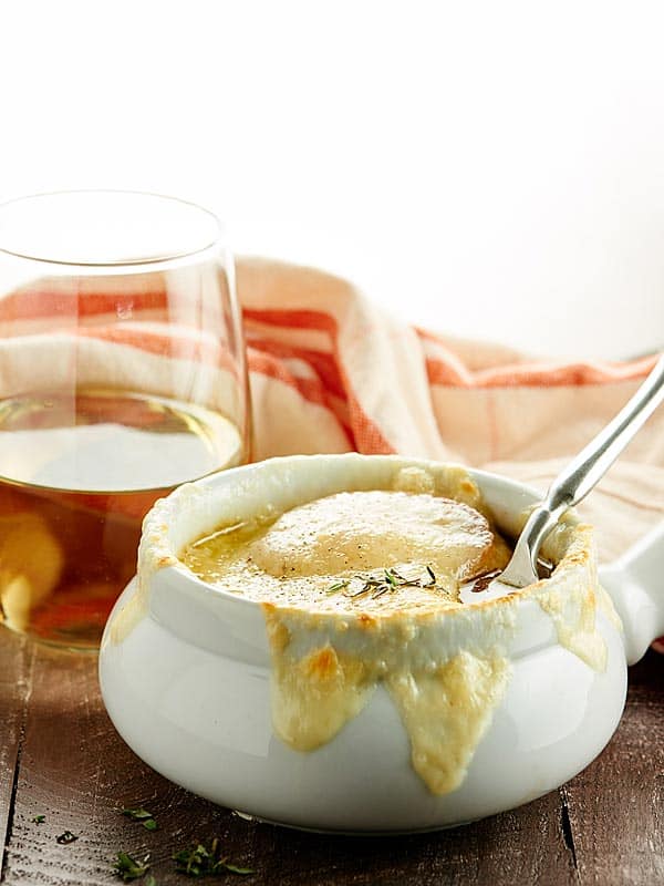 French onion soup bowl with wine glass in background