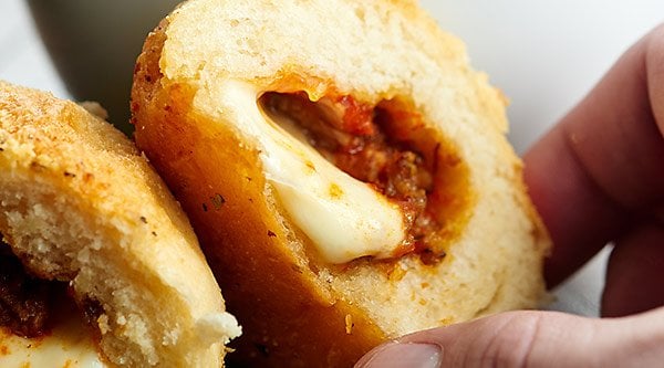 Pre made biscuits are stuffed w/ pizza sauce, cheese, sausage/pepperoni & smothered in butter & pizza spices to make this gooey Stuffed Pizza Rolls Recipe! showmetheyummy.com #pizzarolls #sausagepizza