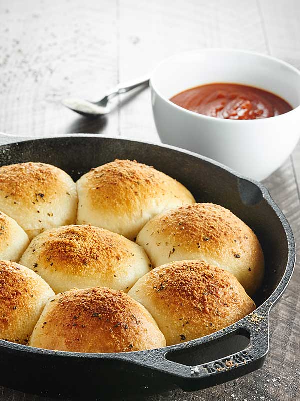 skillet of stuffed pizza rolls next to bowl of marinara