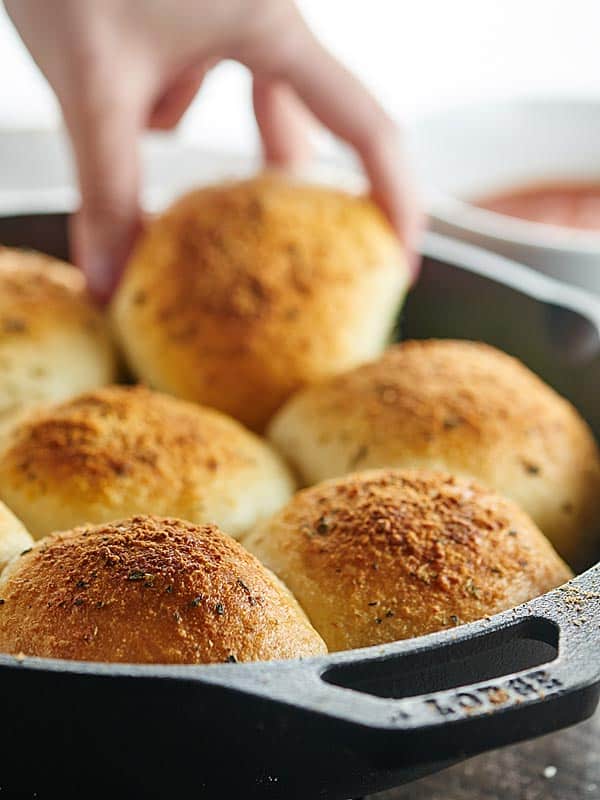 stuffed pizza rolls in skillet, one being picked up