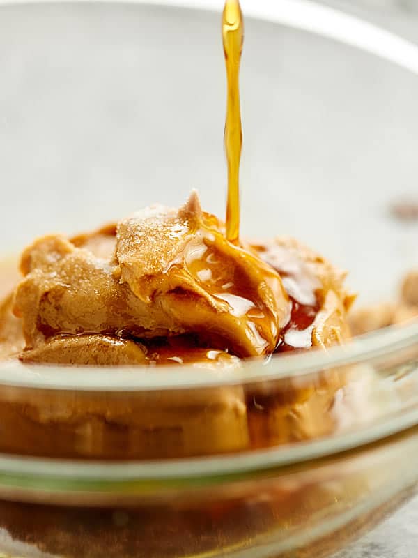 Peanut butter in bowl with honey being drizzled on top