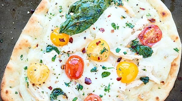 This Chicken Naan Pizza is ready in 20 minutes or less! Garlic naan is topped with a healthy alfredo sauce, diced chicken, mozzarella, tomatoes and basil! showmetheyummy.com #pizza #chickenalfredo