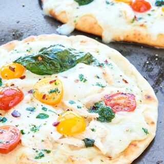 This Chicken Naan Pizza is ready in 20 minutes or less! Garlic naan is topped with a healthy alfredo sauce, diced chicken, mozzarella, tomatoes and basil! showmetheyummy.com #pizza #chickenalfredo