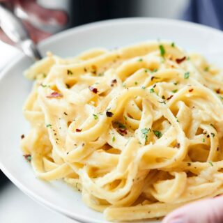 This Healthy Alfredo Sauce is a lightened up version of a classic (130 calories per serving). Made with greek yogurt, skim milk, and parmesan! showmetheyummy.com #healthy #alfredosauce