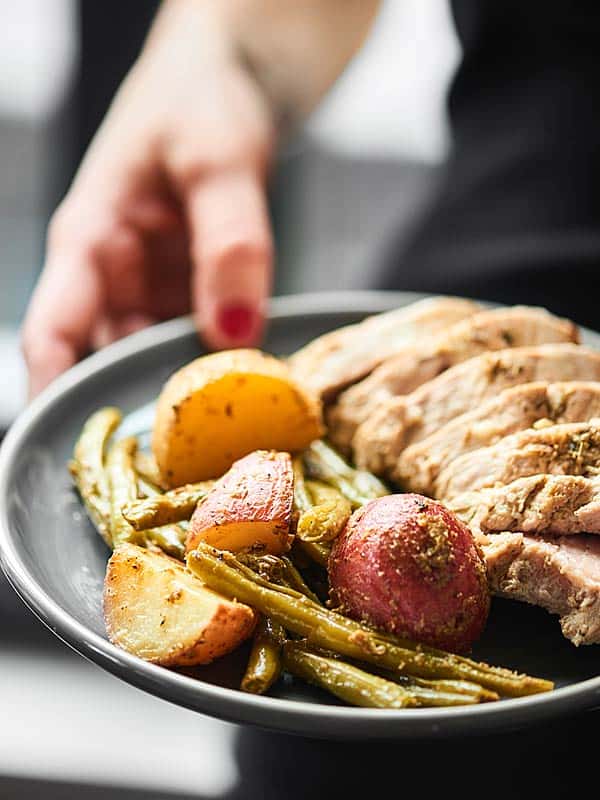 Plate with pork tenderloin and veggies held