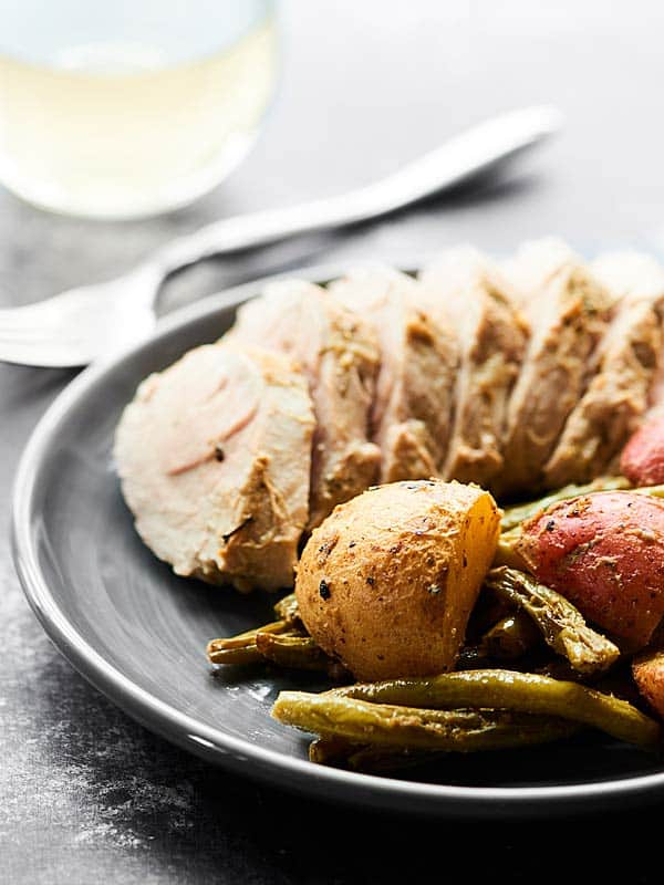 Side view of plate with pork chop and roasted potatoes and green beans