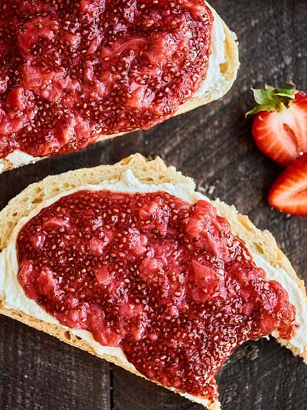 two slices of toast with jam, one with bite out, above