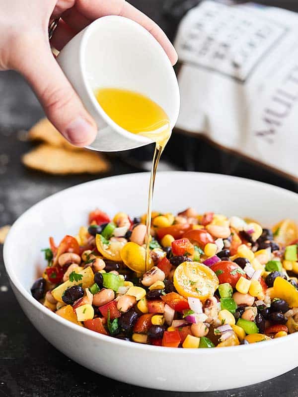 Dressing being drizzled over Texas Caviar in a bowl