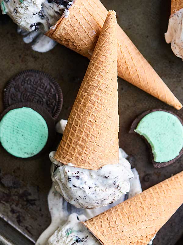 no churn mint oreo ice cream on baking sheet with cones and oreos above