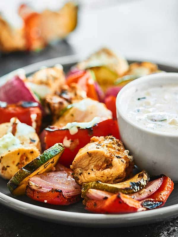 cooked veggies on plate with bowl of tzatziki