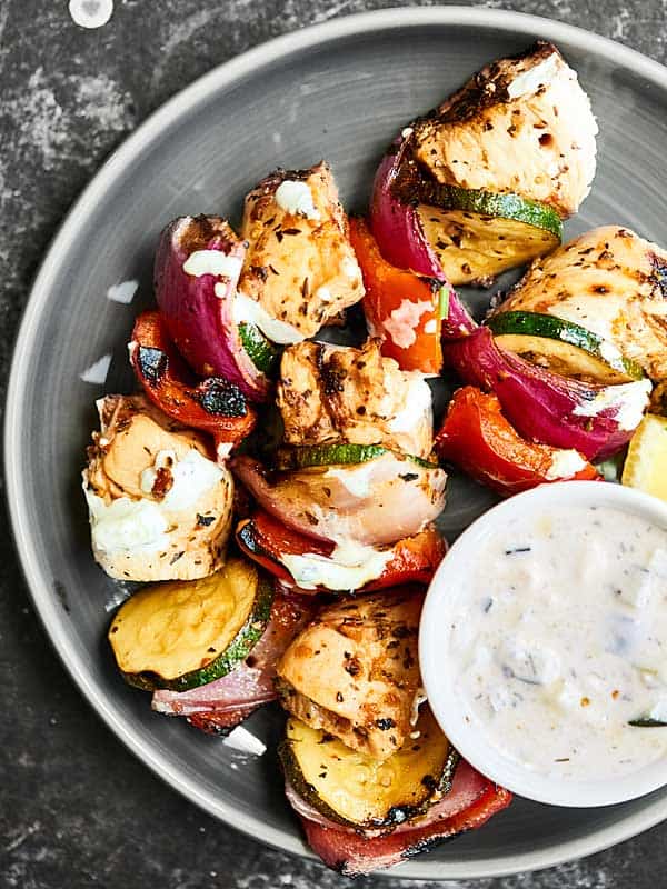 Greek kebabs on plate with bowl of tzatziki above