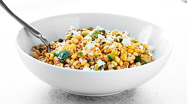 This Mexican Corn Salad will totally be the star of your next BBQ. Full of roasted corn, creamy avocado, fresh cilantro, lime, and tons of spices, it's SO full of texture and flavor. showmetheyummy.com #cornsalad #mexicancornsalad