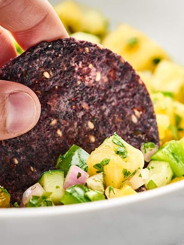 Chip being dipped into pineapple salsa