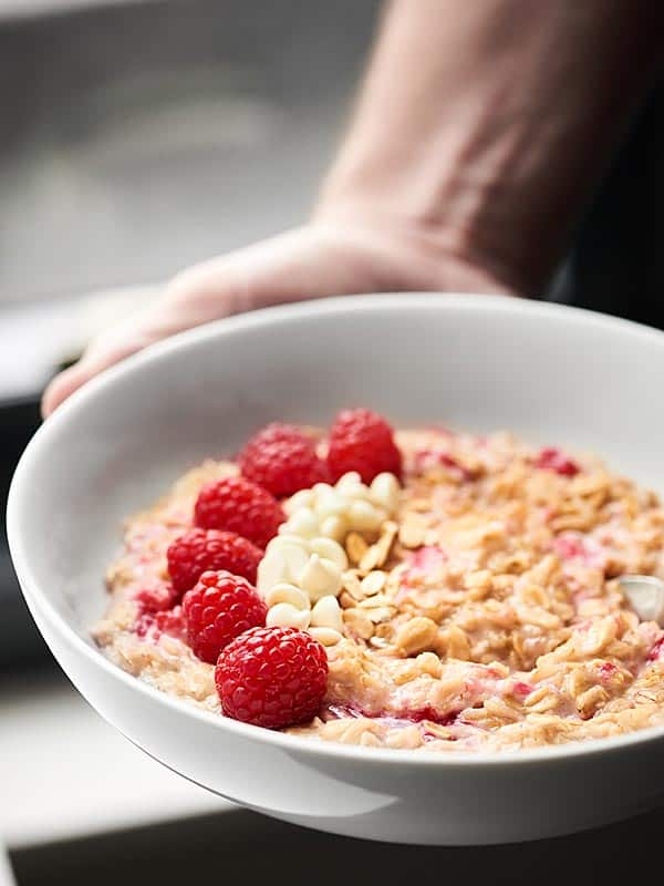 bowl of white chocolate berry cheesecake oatmeal held