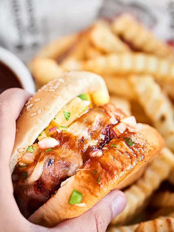 Pork burger on a bun held with fries in the background