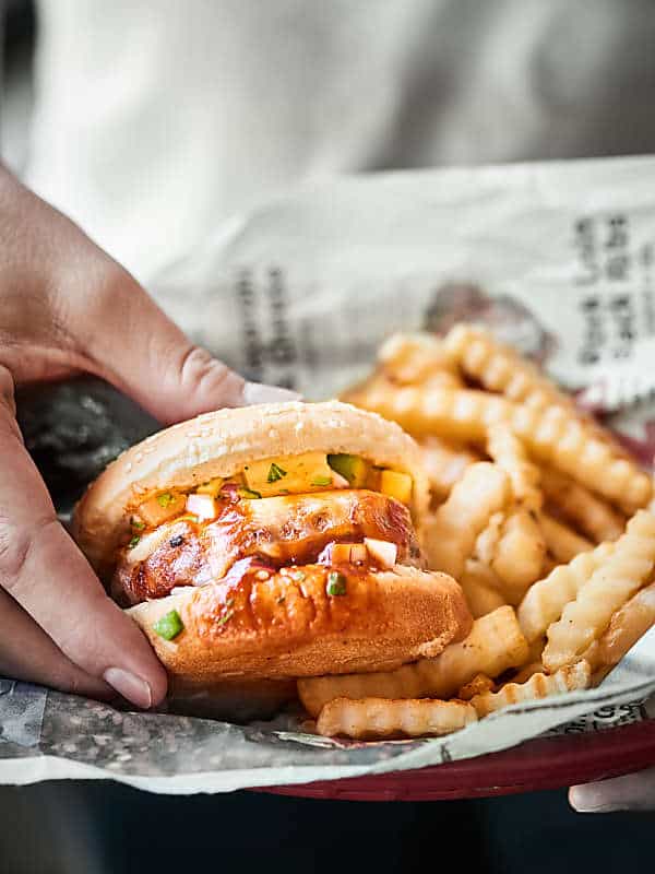 Pork burger on a bun being grabbed off plate