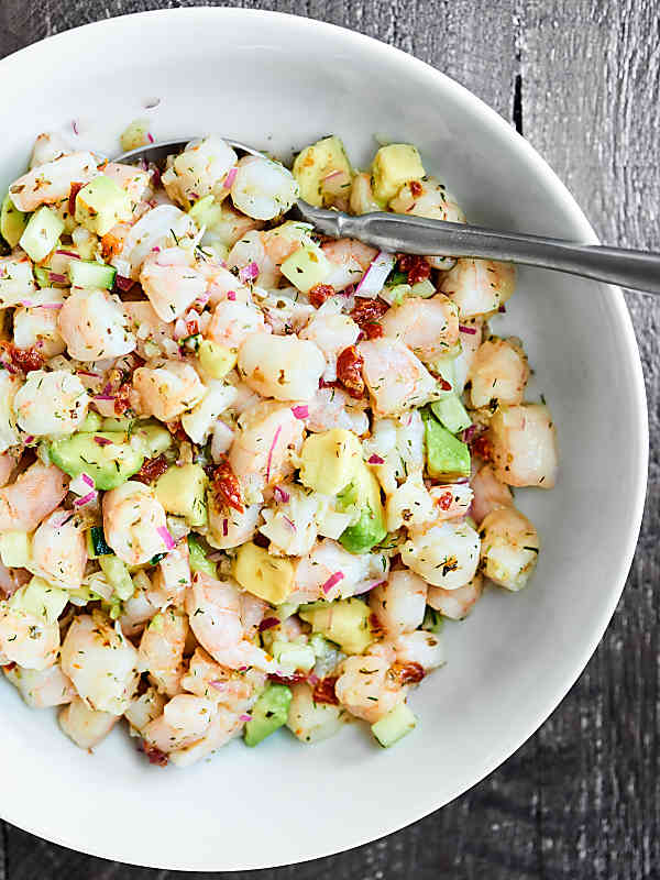 This Shrimp Avocado Salad Recipe is perfect for hot summer days! It's an EASY, cold, no-cook, healthy, refreshing salad full of shrimp, avocado, cucumbers, sun dried tomatoes, lemon juice, spices, and more! showmetheyummy.com #shrimp #avocado