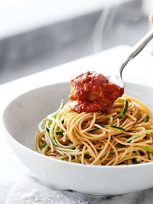 Meatball being placed onto bowl of noodles/zoodles