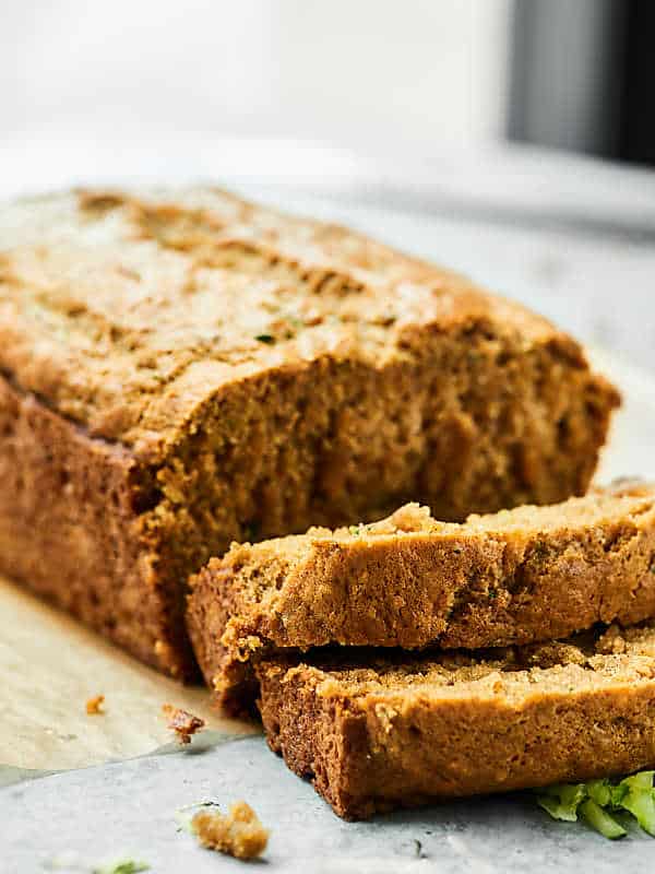 loaf of vegan zucchini bread with some pieces sliced