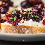 A twist on a classic, this Cherry Bruschetta is the perfect holiday appetizer. Full of sweet dark cherries, pecans, rosemary, thyme, and pinot noir, it comes together in minutes and is paired with a chewy baguette and tangy goat cheese! showmetheyummy.com Recipe made in partnership w/ @BarefootWine #bruschetta #holidayappetizers