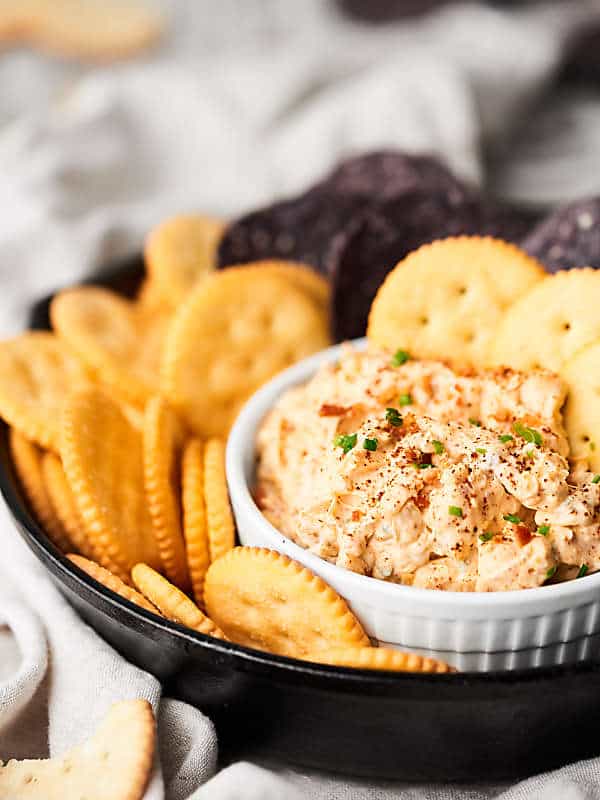 Dip in bowl next to plate of crackers side view