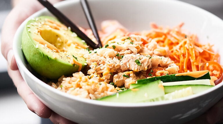 Spicy tuna roll bowl with chopsticks held