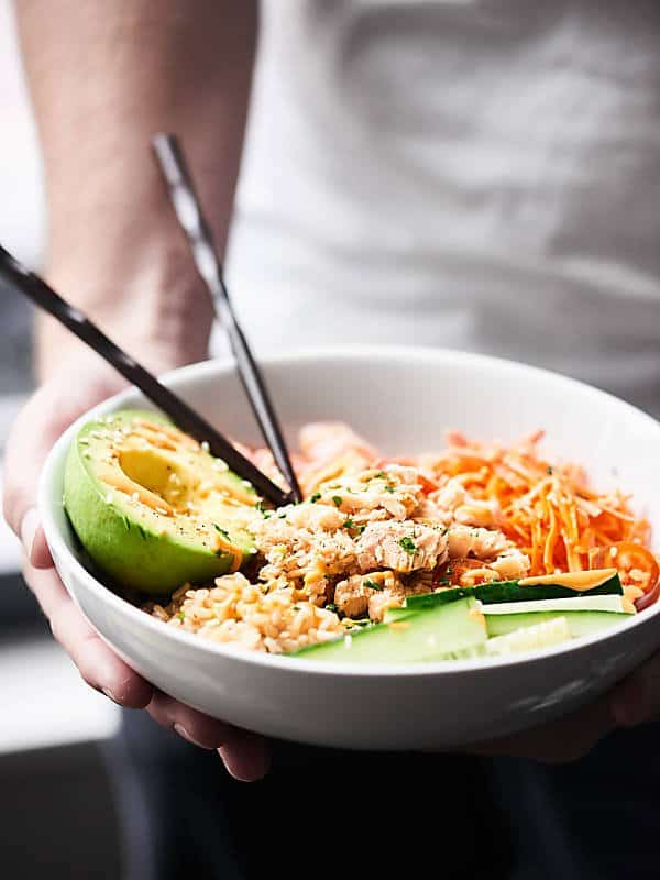 Spicy tuna roll bowl with chopsticks held