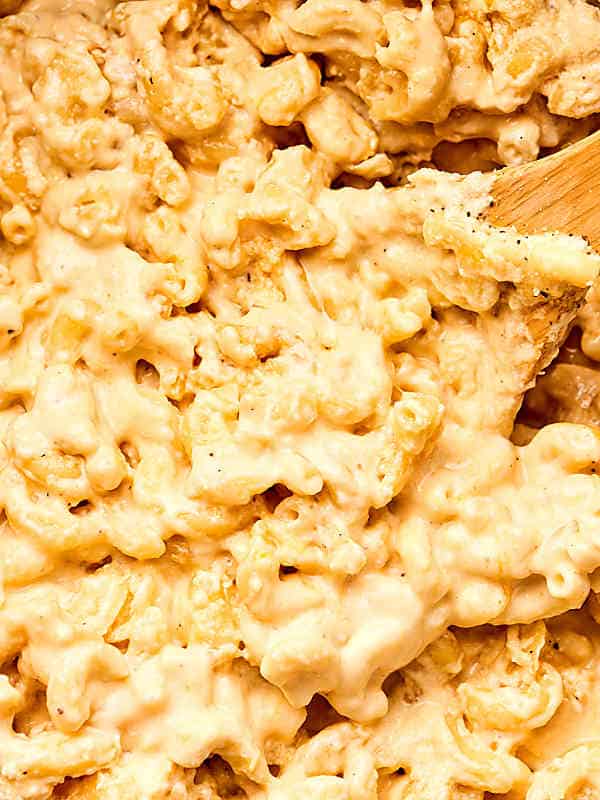 close up of cheesy mac and cheese with wooden spoon