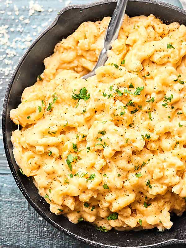 Crock pot mac and cheese in a small skillet dish with a spoon above